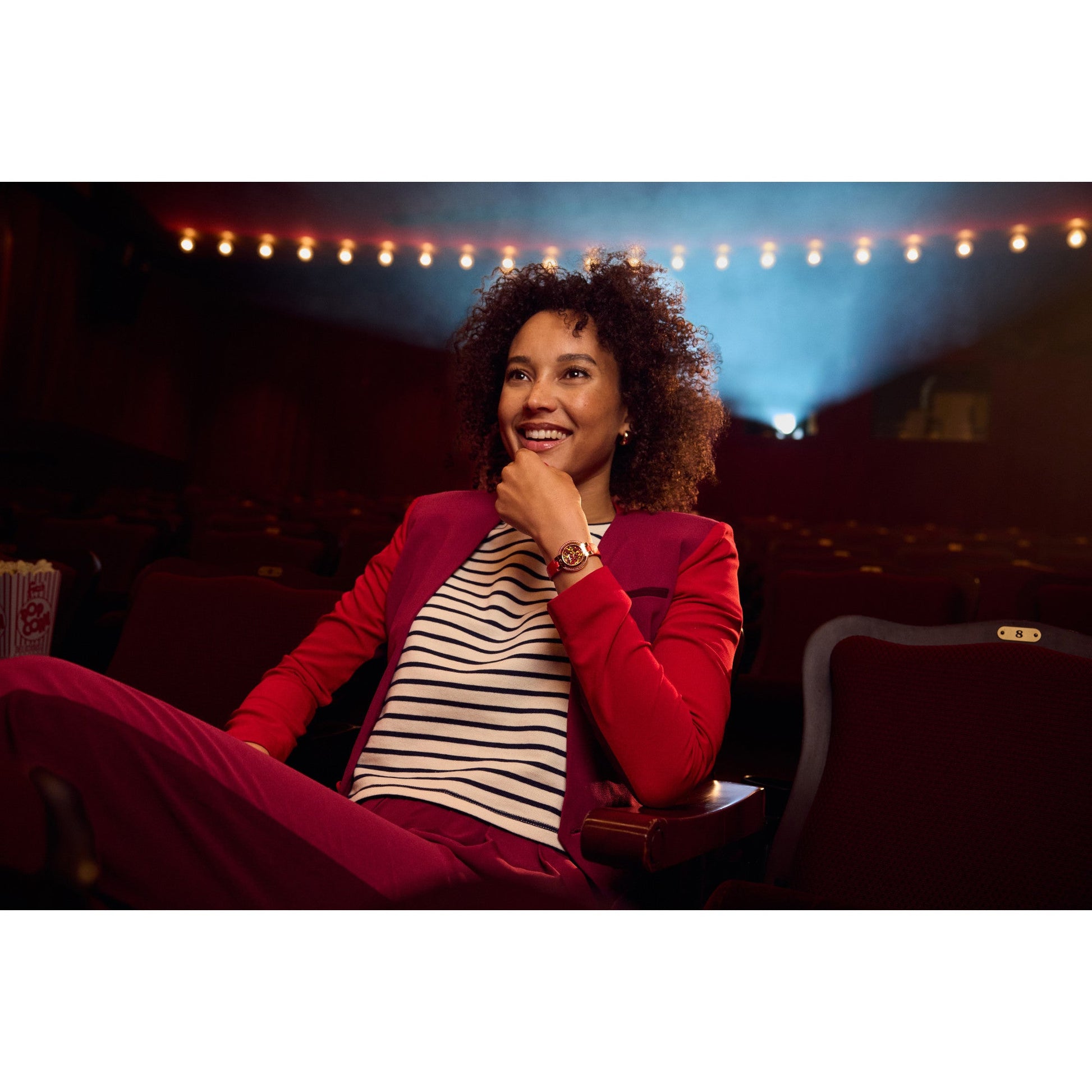 Model wearing Bulova 97R105 watch — vibrant red dial and ruby halo glowing against wrist with graceful autumn-inspired style.