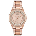 Citizen FE7053-51X Drive watch featuring a pink gold-tone stainless steel case, light pink dial with luminous rose gold-tone dauphine-style hands and index hour markers, Arabic numerals at 3, 6, 9, and 12 o'clock positions, and matching bracelet—front view.